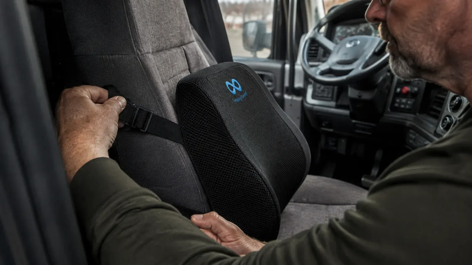 An Everlasting Comfort lumbar pillow strapped to a truck bucket seat with adjustable black straps